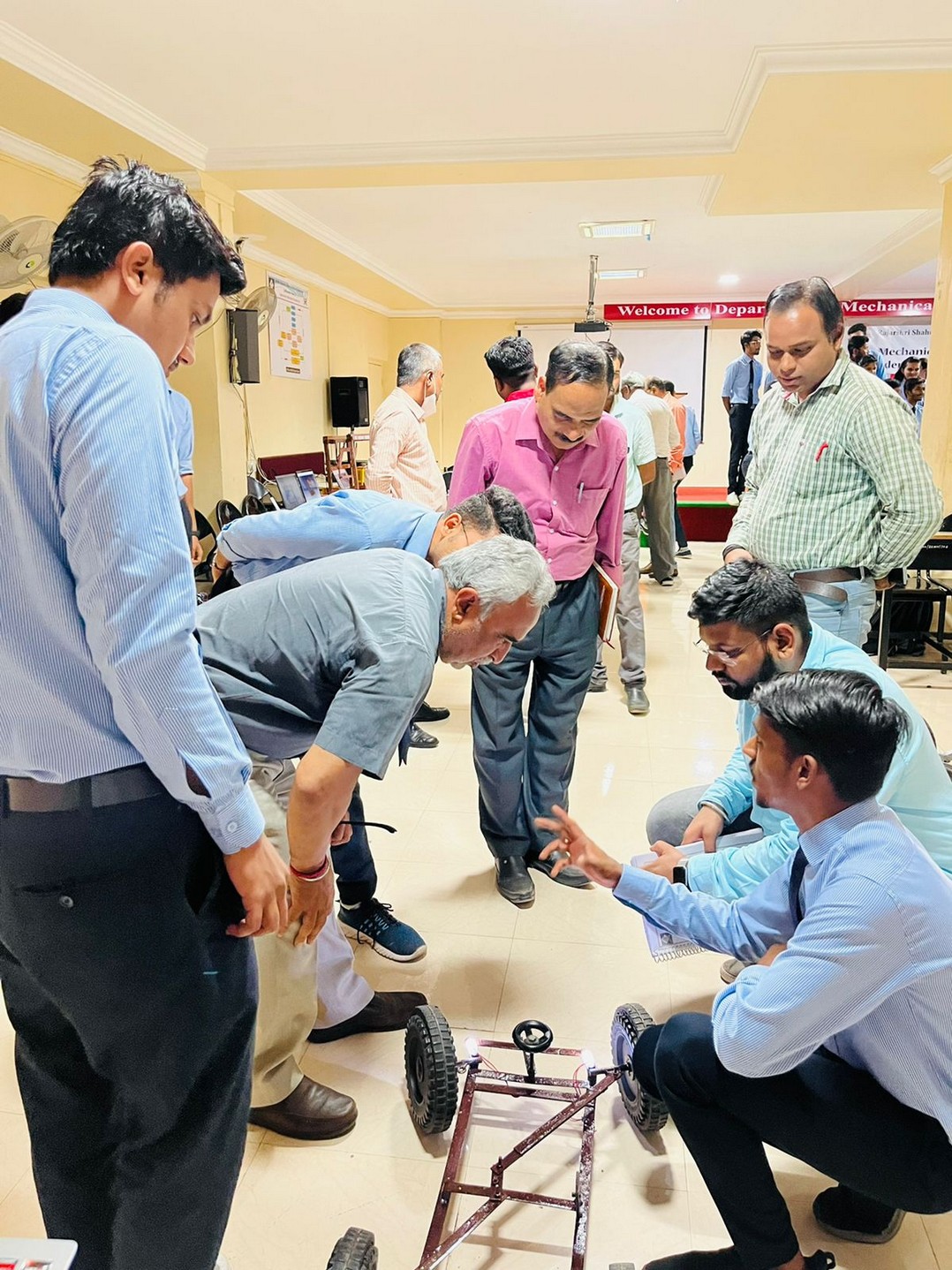 Faculty and students examining a wheeled mechanical prototype